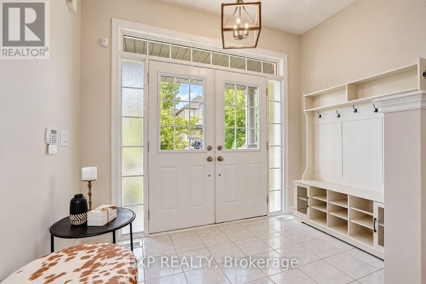 Foyer with tiled floor, white double doors, and a built-in white storage unit with hooks. - 240 Aspenwood Drive, Newmarket