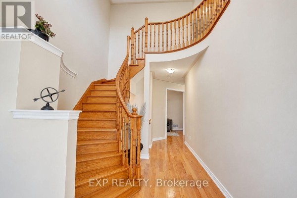 Interior view of a grand staircase with wooden steps and railings, leading to the second floor. - 240 Aspenwood Drive, Newmarket