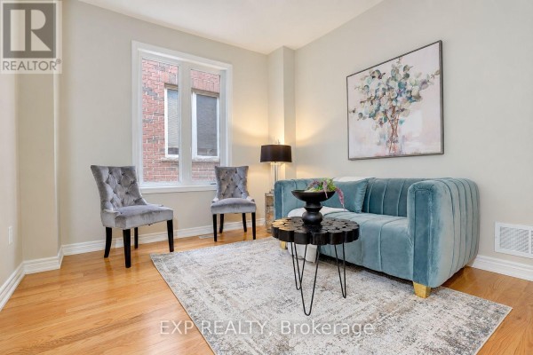 Living room with a teal sofa, two grey accent chairs, a black coffee table, and a patterned rug. - 240 Aspenwood Drive, Newmarket