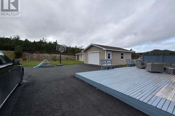 Backyard view with a detached garage, wooden deck, outdoor seating, basketball hoop and swing set. - 240 Bonds Path, Placentia