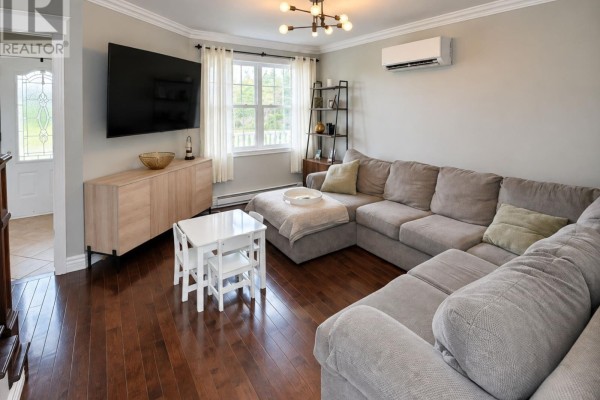 Living room with a large sectional sofa, television, media console, and hardwood floors. - 240 Bonds Path, Placentia
