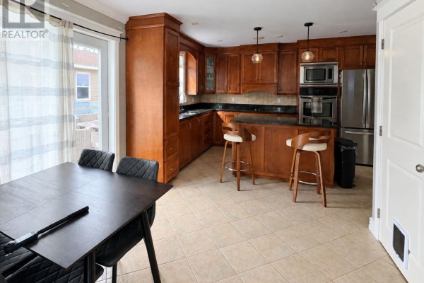 Kitchen and dining area with cherry wood cabinets, island, and dark dining table with chairs. - 240 Bonds Path, Placentia