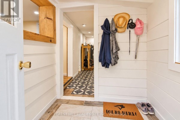 Interior view of a mudroom with white shiplap walls, coats hanging, and an open doorway to a hallway. - 240 Britannia Road, Huntsville