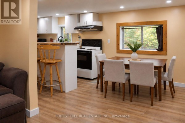 Open concept kitchen and dining area with white cabinets, black appliances, and a wood-framed window. - 240 Britannia Road, Huntsville