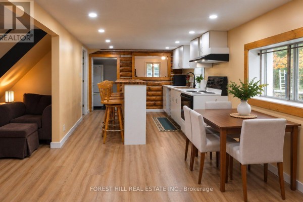 View of the kitchen and dining area, featuring a breakfast bar with stools and a dark sectional sofa. - 240 Britannia Road, Huntsville