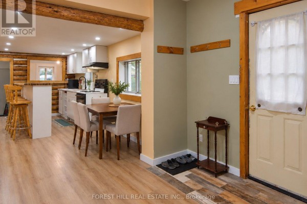 View of the entry door and adjacent dining area with a wooden breakfast bar and kitchen counter. - 240 Britannia Road, Huntsville