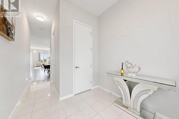 Foyer with white tile flooring, light gray walls, and a mirrored console table. - 240 Elyse Court, Aurora