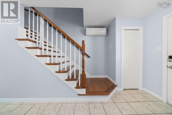 Interior view of a wooden staircase with white spindles and a light blue wall. - 240 James Street, Timberlea