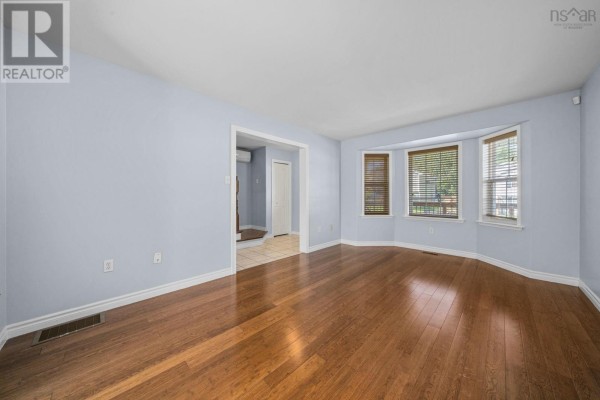 Empty living room with light blue walls, hardwood floors, and a bay window. - 240 James Street, Timberlea