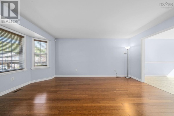 Spacious living room with hardwood floors, a bay window, and an open doorway to another room. - 240 James Street, Timberlea