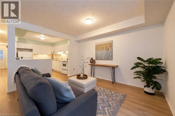 Living room looking towards an open-concept kitchen area with white cabinets. - 240 London Road W Unit# 71, Guelph