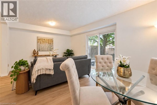 Living room with glass dining table and upholstered chairs, adjacent to the living area. - 240 London Road W Unit# 71, Guelph