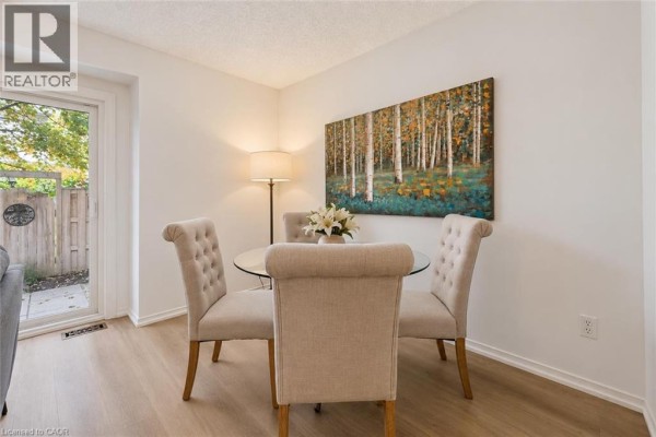 Dining area with glass table, upholstered chairs, and artwork on the wall. - 240 London Road W Unit# 71, Guelph