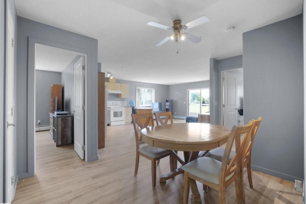 Apartment dining area with oval wood table and chairs, adjacent to open-concept kitchen and living space. - 240 Spruce Ridge Rd, Spruce Grove