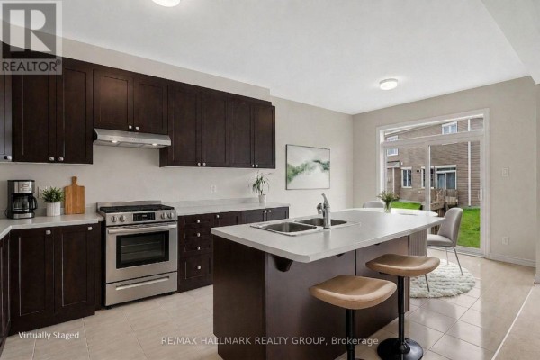 Modern kitchen with dark cabinets, island, and yard view - 240 Sweetvalley Drive Ottawa