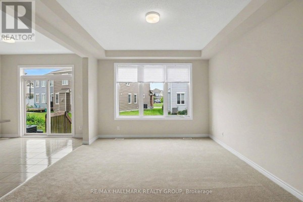 Living room with tray ceiling, large window, and sliding door to deck - 240 Sweetvalley Drive Ottawa