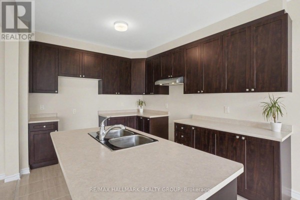 Kitchen with dark wood cabinets, island, and double sink - 240 Sweetvalley Drive Ottawa