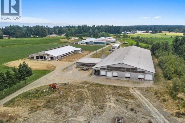 Wide aerial shot of the farmstead showing multiple large agricultural buildings and surrounding fields. - 2400 Ployart Rd, Black Creek