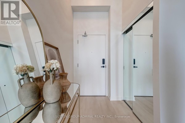 Apartment entryway with a white door, keyless entry, and mirrored closet doors. - 2401 - 3900 Confederation Parkway, Mississauga