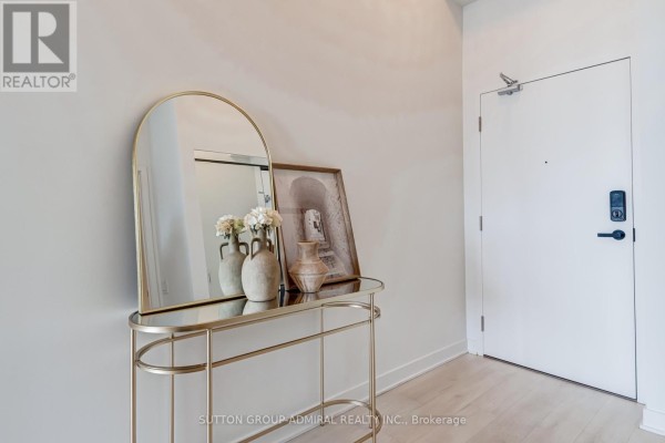 Apartment foyer with a gold arched mirror, decorative vases, and a white door. - 2401 - 3900 Confederation Parkway, Mississauga