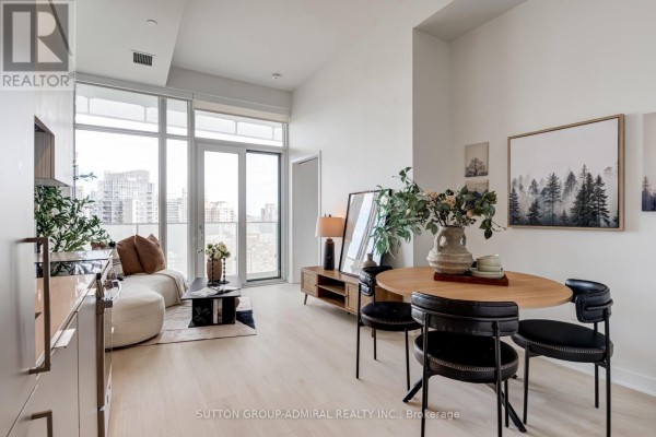 Open concept living and dining area with floor-to-ceiling windows and modern furniture. - 2401 - 3900 Confederation Parkway, Mississauga