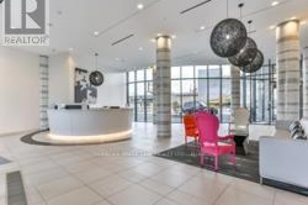 Building lobby with a reception desk, modern pendant lights, and colorful seating. - 2401 - 51 East Liberty Street, Toronto