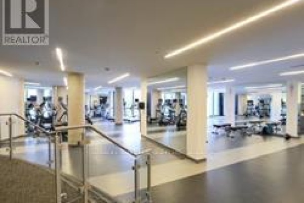 Spacious gym with cardio machines, weight racks, and mirrored walls. - 2401 - 51 East Liberty Street, Toronto