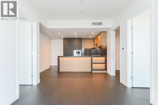 View of an open-concept living area and modern kitchen through doorways. - 2401 6608 Sussex Avenue, Burnaby