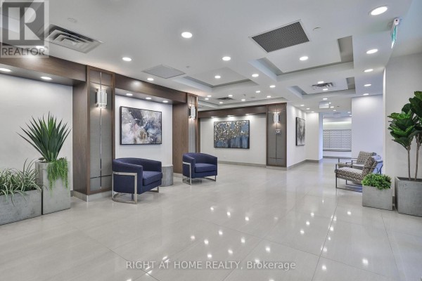 A spacious building lobby with tiled floors, modern furniture, and abstract art. - 2402 - 3 Michael Power Place, Toronto