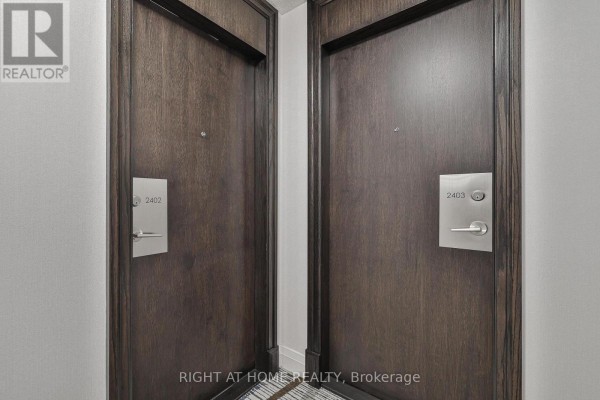 Two dark wood apartment doors with polished metal hardware and room numbers. - 2402 - 3 Michael Power Place, Toronto