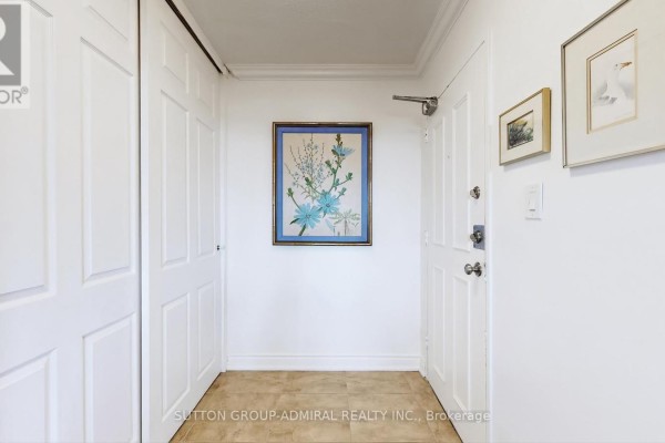 Apartment entryway with white doors, beige tiled floor, and framed artwork on the wall. - 2402 - 85 Emmett Avenue, Toronto