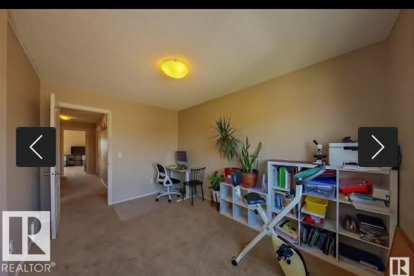 Home office with a desk, chair, exercise bike, and cube shelving unit. - 2402 Casselman Cr Sw, Edmonton