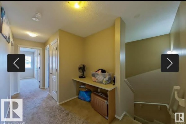 Upstairs hallway with beige carpet, doors, and a built-in desk area. - 2402 Casselman Cr Sw, Edmonton