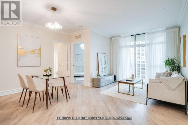 Living and dining area with light wood floors, beige sofa, and glass dining table. - 2403 - 78 Harrison Garden Boulevard, Toronto