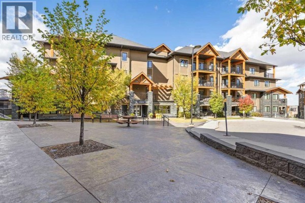 Exterior view of a multi-story apartment building with balconies and trees. - 2405, 450 Kincora Glen Road Nw, Calgary