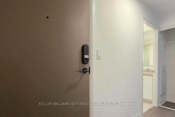 Apartment entrance door with a digital lock, peephole, and a light switch on a white wall. - 2405 - 4015 The Exchange Drive, Mississauga
