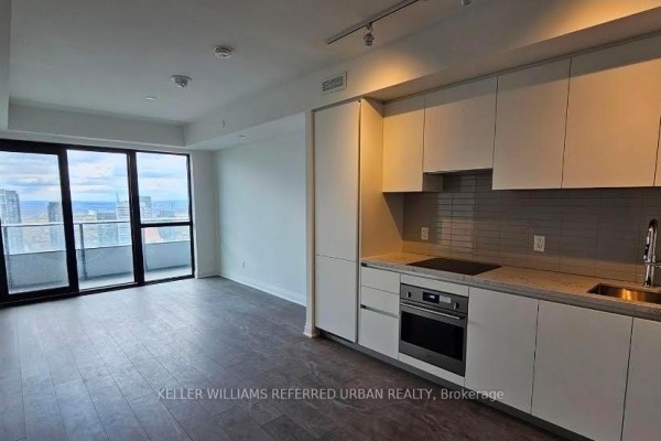 Open concept living area with a balcony and a modern kitchen featuring white cabinets and stainless steel appliances. - 2405 - 4015 The Exchange Drive, Mississauga