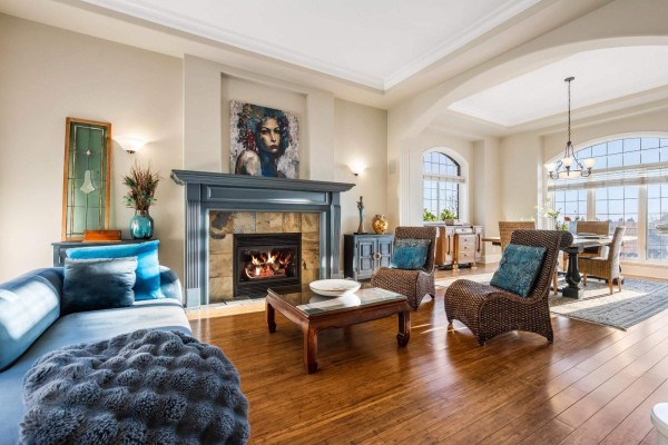 Living room with a fireplace, wicker chairs, a sofa, coffee table, and dining area beyond. - 2405 Cranberry Court, Abbotsford
