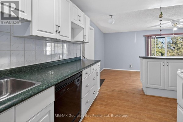 Open kitchen area with white cabinetry, green countertops, and a view of the living space. - 2407 Rumney Road, Tay