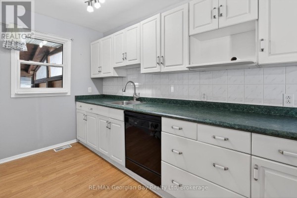Close-up of kitchen cabinetry with green countertops and a window for natural light. - 2407 Rumney Road, Tay