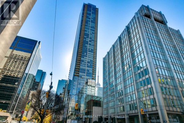 Wide shot of a tall glass skyscraper in a city with clear blue sky. - 2408 - 180 University Avenue, Toronto