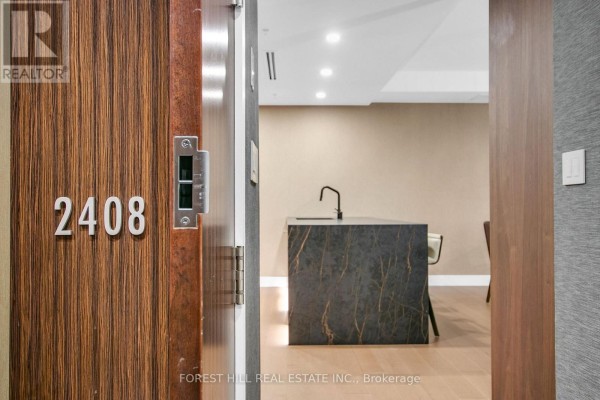Apartment door 2408 opens to a modern kitchen island with dark marble. - 2408 - 180 University Avenue, Toronto