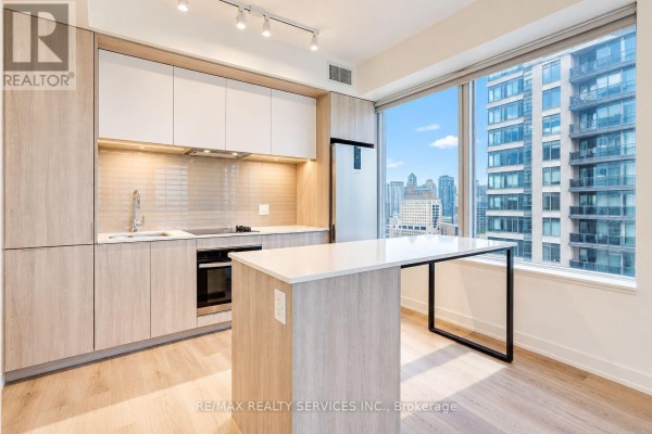 Modern kitchen with light wood cabinets, white countertops, stainless steel appliances, and island. - 2408 - 395 Square One Drive, Mississauga