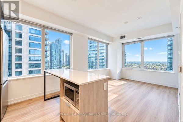 Apartment living area with large windows, kitchen island, and city view. - 2408 - 395 Square One Drive, Mississauga