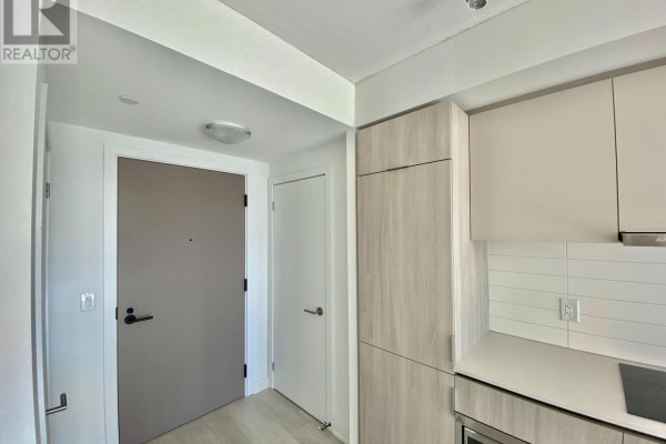 Apartment hallway with a grey front door, white closet door, and light wood cabinetry. - 2408 - 47 Mutual Street, Toronto