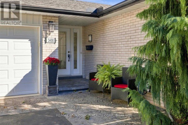 Covered front porch with brick facade, glass-paned double doors, and seating. - 2408 Hereford Crescent, Burlington