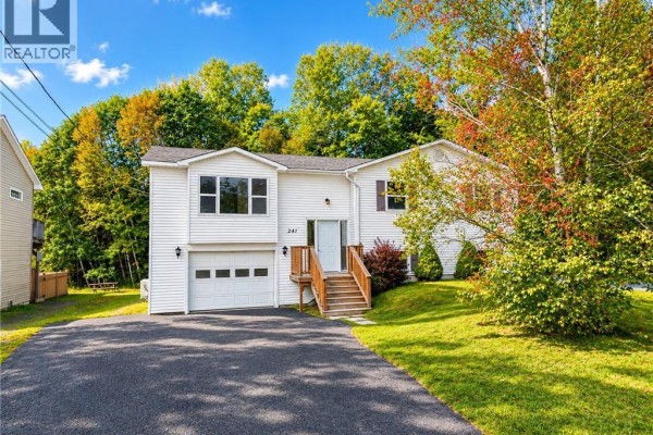 White split-level house with attached garage, wooden stairs, and green lawn. - 241 Claudie Road, Fredericton