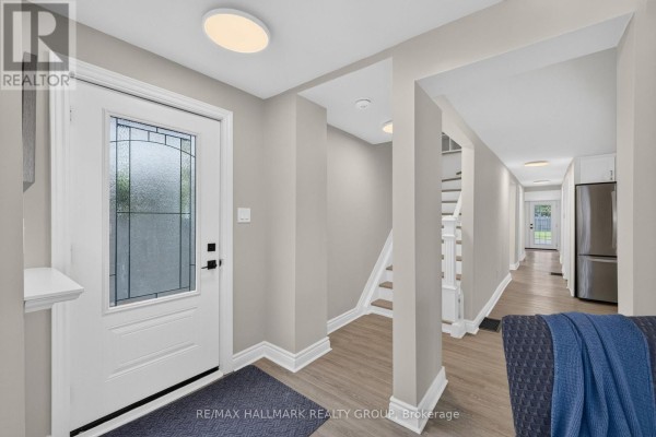 Interior view of a bright entryway with a glass-paned front door and light grey walls. - 241 Lewis Street E, Edwardsburgh/cardinal