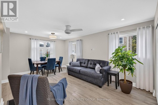 Living and dining area with grey sofa, armchair, dark wood dining table, and blue chairs. - 241 Lewis Street E, Edwardsburgh/cardinal