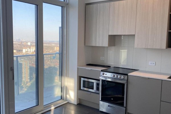 Apartment kitchen with sliding glass doors offering a city view and light wood cabinets. - 2410 - 3900 Confederation Parkway, Mississauga
